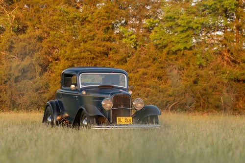 Dice-Magazine-Tom-Busch-Ford-17 Vintage black car parked in a grassy field with autumn trees in the background.