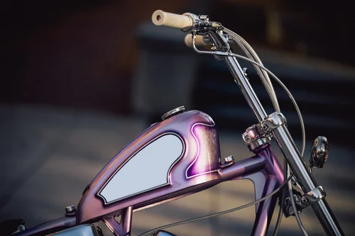 Hunter+Kelly-Unity+MFG-1953+Panhead-Turbo+Lover-1181 Purple metallic bike with a retro-style fuel tank and chrome handlebars, beige grips.