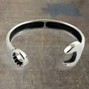 Open-ended silver cuff bracelet with rounded, polished ends resting on a textured surface.