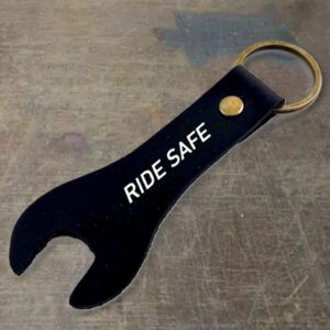 Black metal bottle opener attached to a key ring, with a gold rivet and the words 'RIDE SAFE' printed in white.